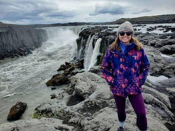 a reviewer in front of a waterfall wearing the purple leggings