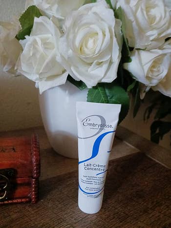 a tube of cream in front of white roses