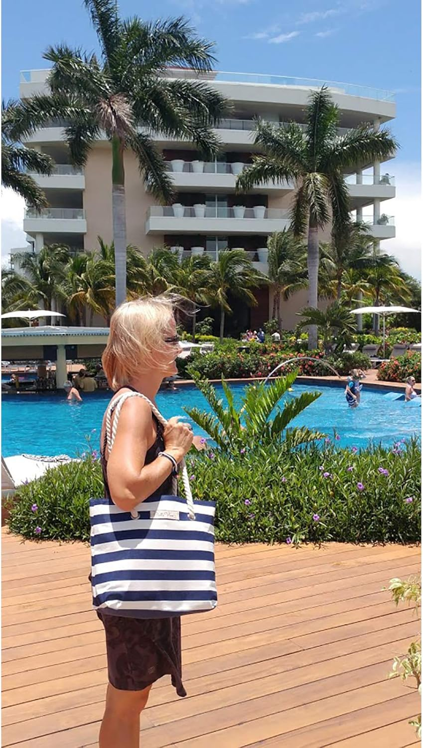 A person carrying a striped tote bag stands near a pool with people swimming and lounging. A multi-story building with palm trees is in the background