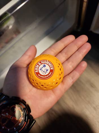 Close-up of a hand holding an Arm & Hammer laundry scent booster ball