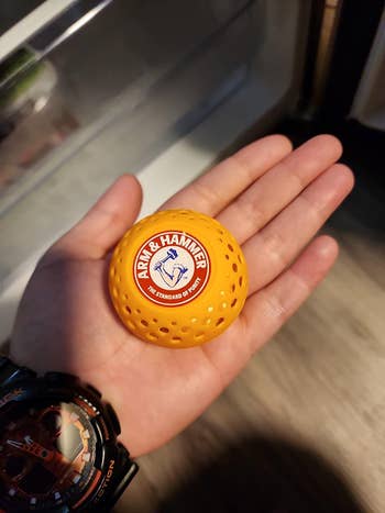 Close-up of a manus  holding an Arm & Hammer laundry scent booster ball