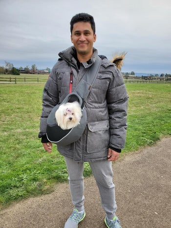 reviewer wearing the sling with their small maltese inside