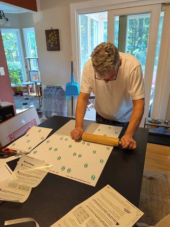 reviewer using a rolling pin to press the puzzle saver sheets onto a puzzle