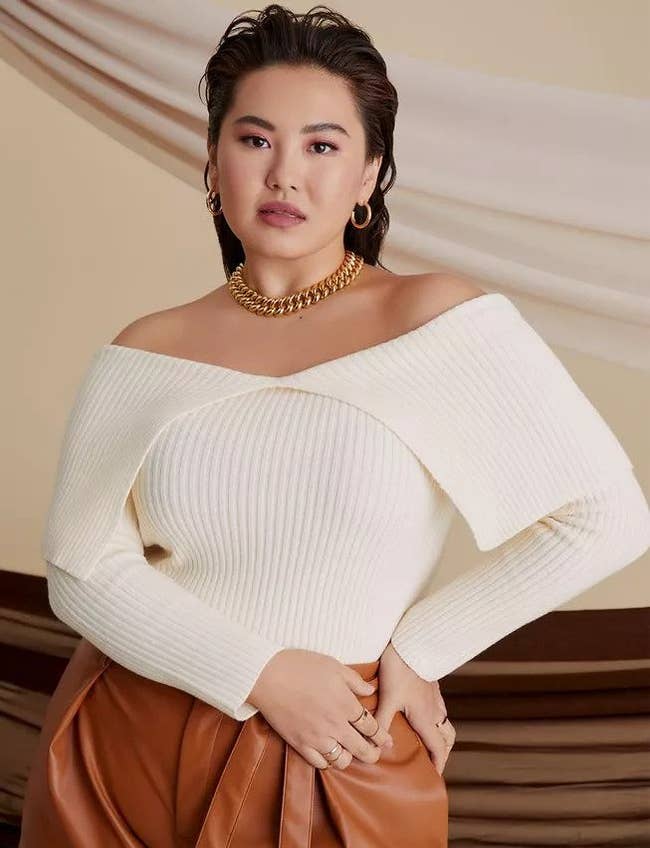 Model wearing  buttercream off-the-shoulder sweater with leather pants