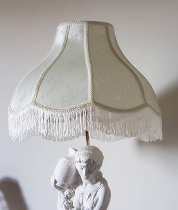 Elegant lamp with a fringe shade and a sculpted figure base