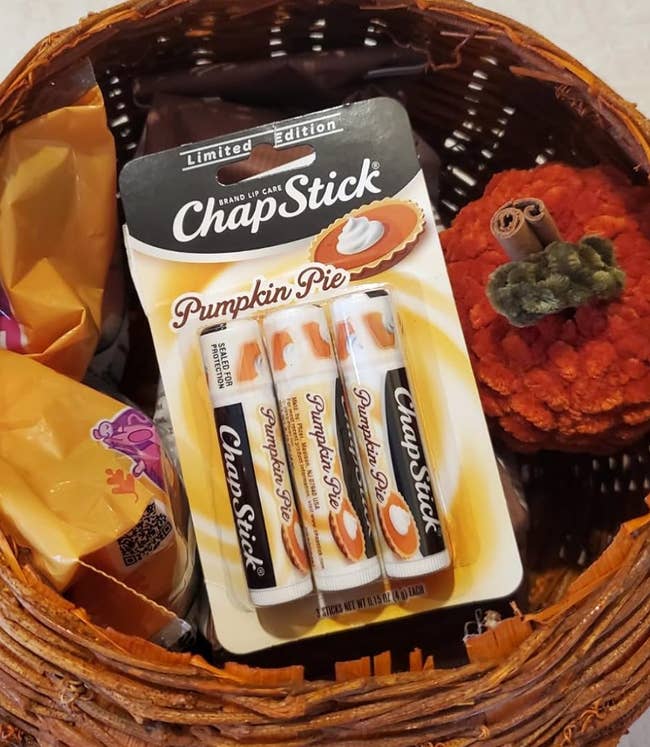 Basket with constricted  variation  Pumpkin Pie ChapStick bundle  surrounded by fall-themed items similar  a pumpkin decoration and snacks