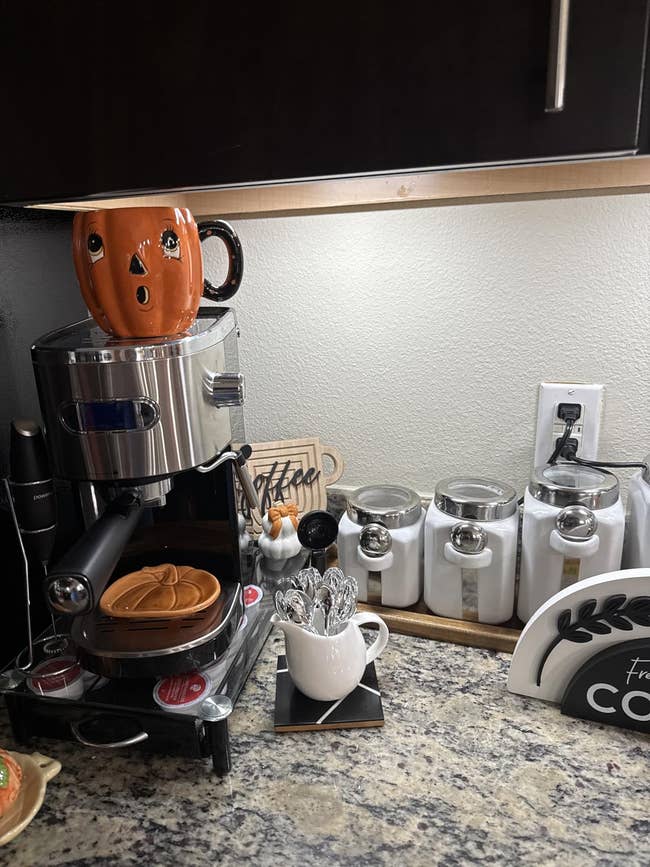 Festive location java presumption with espresso machine, pumpkin-themed mug, and spoons. Decor includes a