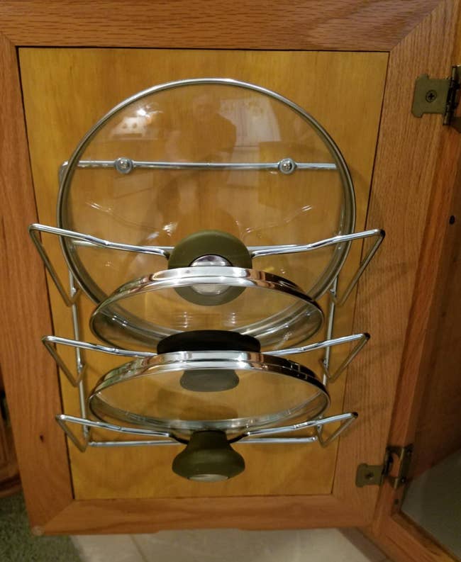 reviewer photo of the rack hanging behind a cabinet holding three pot lids