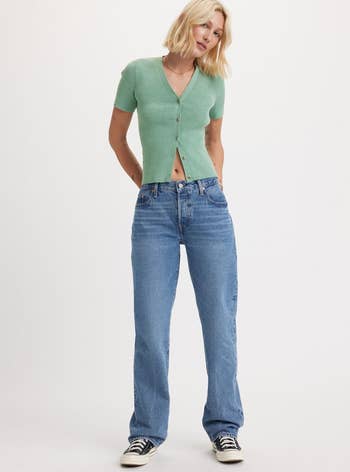 Model poses in a cropped green cardigan and high-waisted jeans