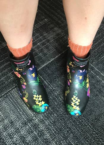 reviewer in the black rain boots with colored floral designs