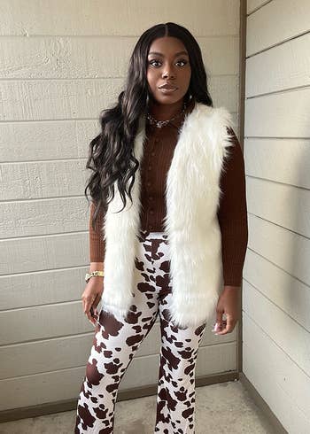 Reviewer in cow-print pants and fur-trimmed vest, posing for a fashion-focused shopping article