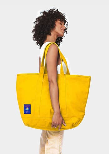 Model with the yellow canvas mega-tote Baboon To The Moon bag slung over their shoulder