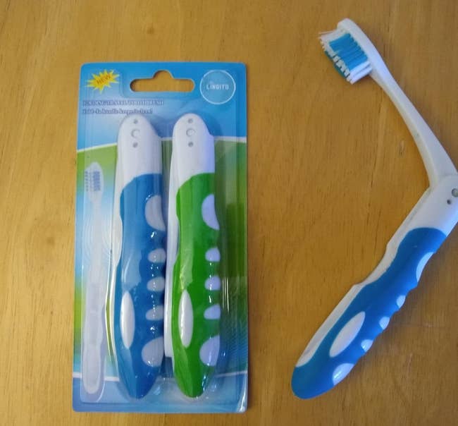 two blue and green toothbrushes folded compactly in the packaging and another one opened to reveal the brush head