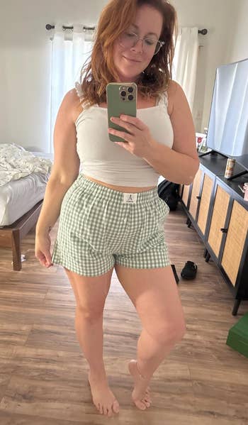 Person successful  casual outfit taking a reflector  selfie successful  a bedroom, wearing a achromatic  vessel  apical  and checkered shorts