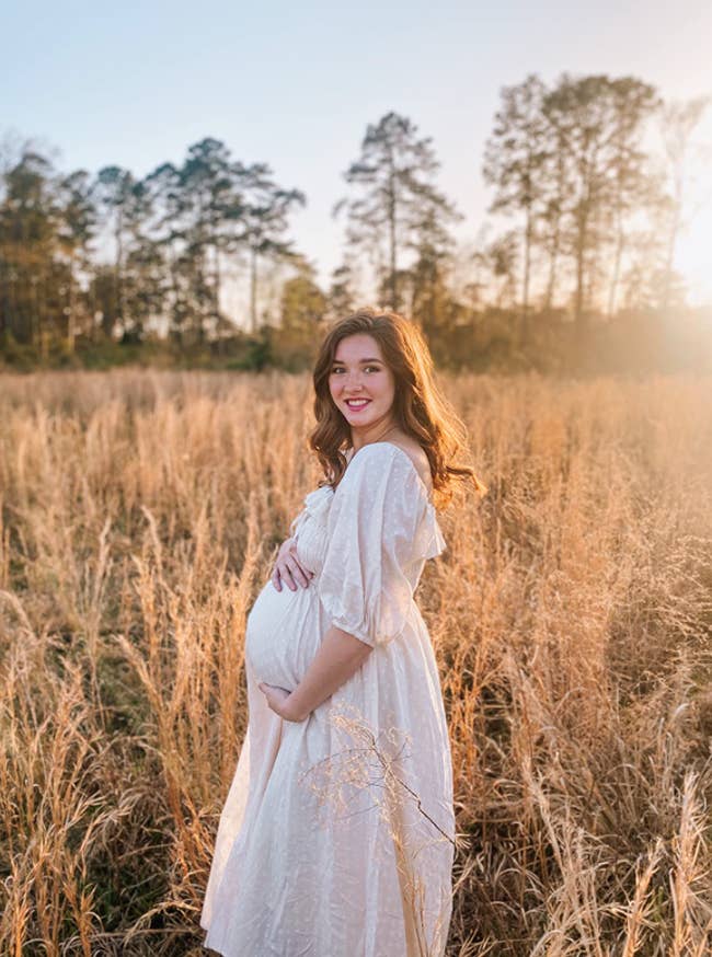 pregnant person in a field wearing a maxi dress