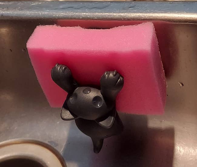 Holder that looks like a black cat holding sponge up with its paws in reviewer's sink