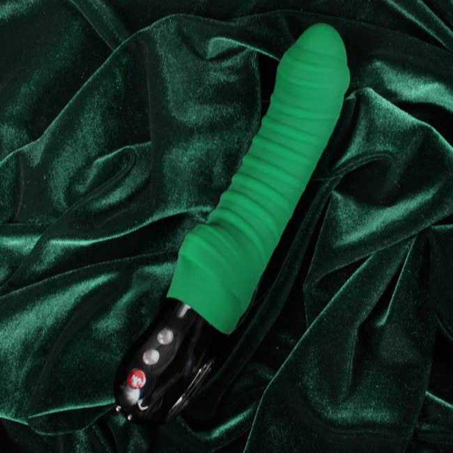 Green vibrator on velvet background
