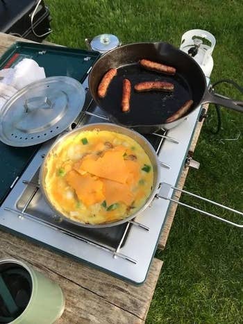 reviewer photo of stainless steel cooking frypan and cast iron pan over camp stove