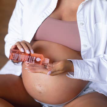 Pregnant model applying large bottle of bio-oil to belly