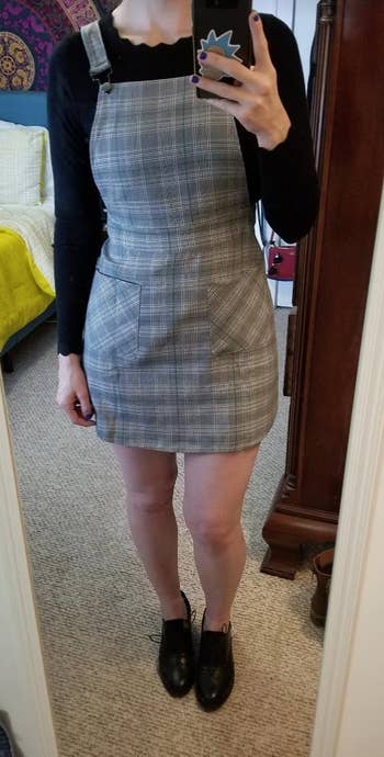 Person successful plaid pinafore formal with achromatic agelong sleeves and achromatic shoes, lasting successful beforehand of a mirror