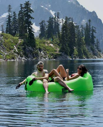 Product in green floating in water with two people lounging on top of it