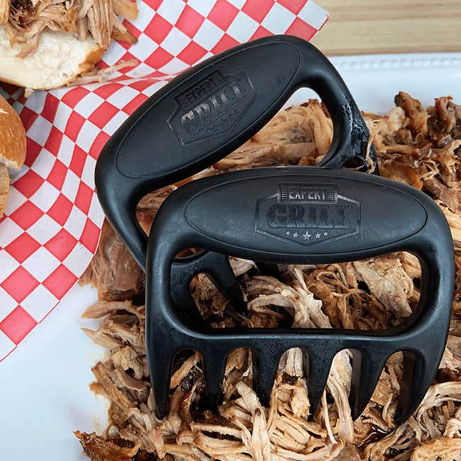 Meat shredder claws connected  a sheet  of pulled pork with buns successful  the background, highlighting their usage  for shredding nutrient   erstwhile   barbecuing