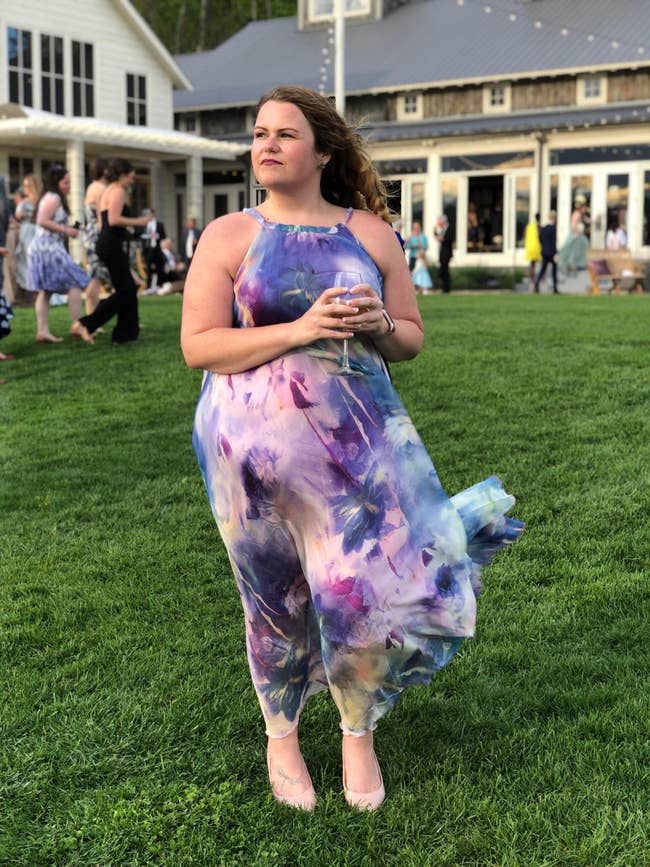 Reviewer standing in grass in a purple floral flowy dress