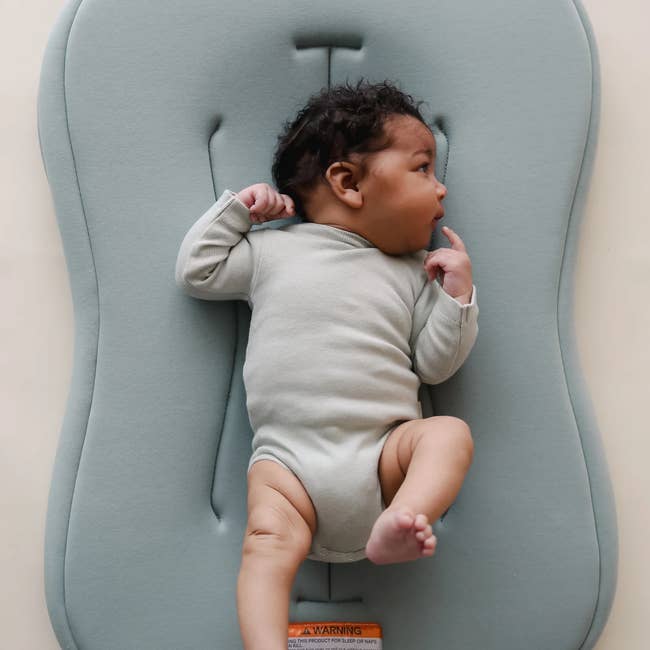 Infant lying connected a cushioned babe lounger looking to the side, wearing a long-sleeve onesie, perfect for caller genitor shopping