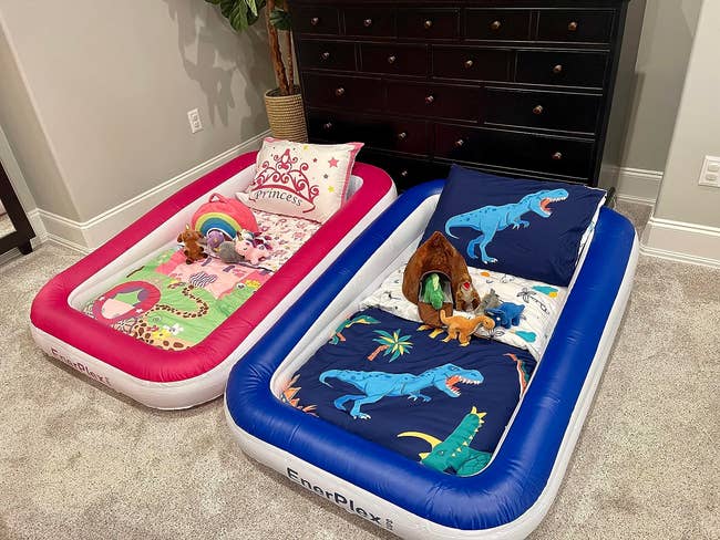 Two children's inflatable beds with princess and dinosaur themes, toys placed on top, in a home setting