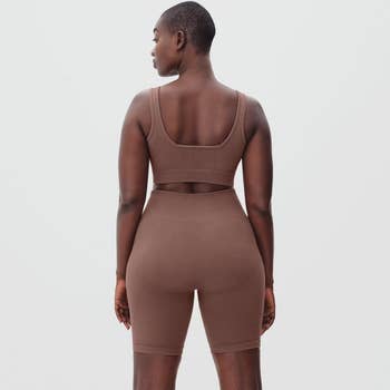 back of a model wearing a matching ribbed bike short and sports bra set in the color 
