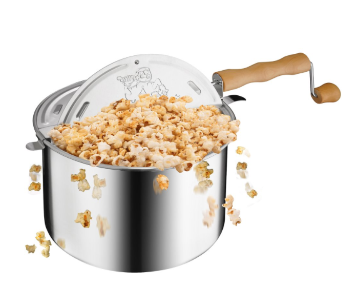 A metallic popcorn popper with popcorn flying out of it.