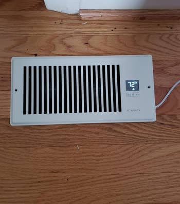 a reviewer photo of the booster fan installed on a floor vent 