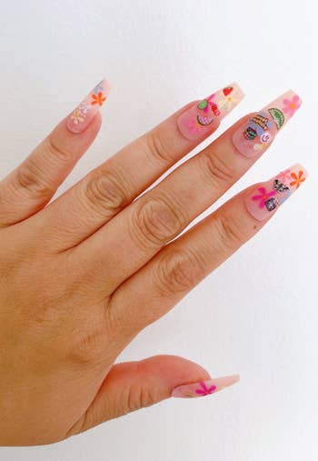 person wearing various harry styles nail stickers on nails