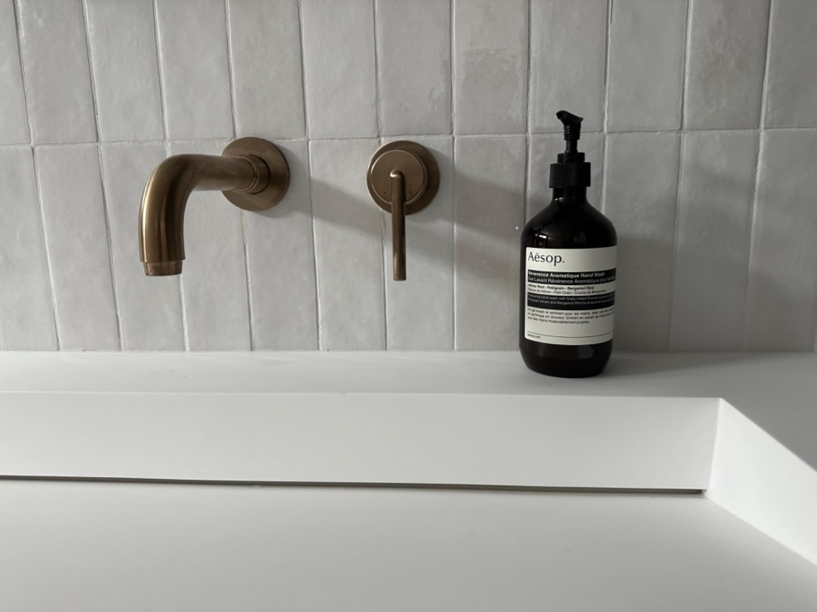 Modern bath  descend  with wall-mounted faucet and a vessel  of Aesop manus  soap connected  the counter