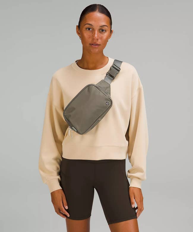 model wearing the green belt bag across their chest