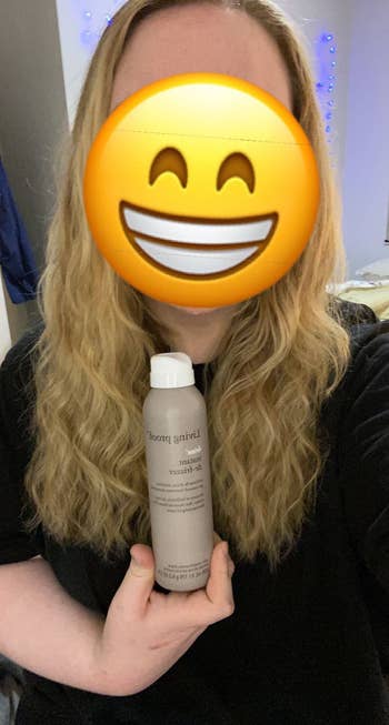 Person with an emoji look   holds a vessel  of hairsbreadth  product. Long, wavy hairsbreadth  is visible. The mounting  appears casual, perchance  a location  environment