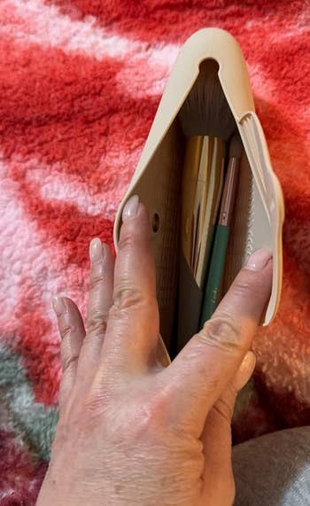 reviewer holding an open tan holder brushes inside