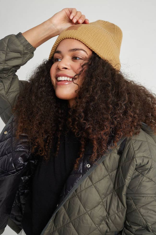 a model wearing a camel colored beanie