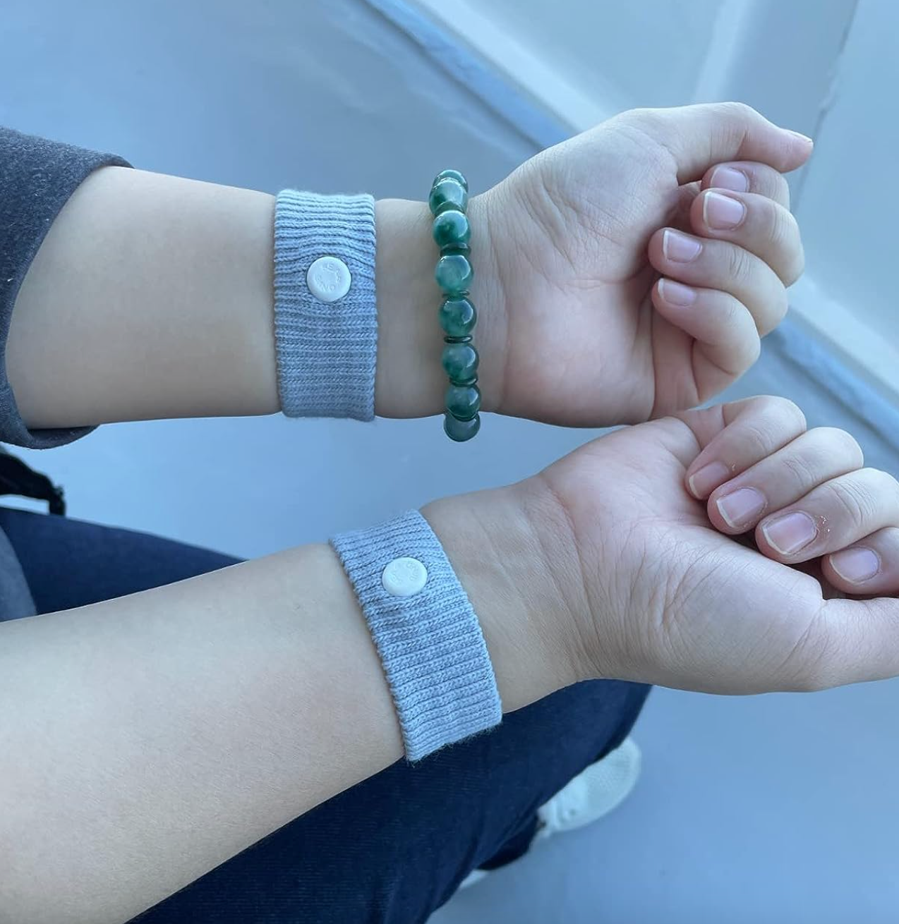 Reviewer with two thick gray bands on their wrists with a white pressure point in the middle 