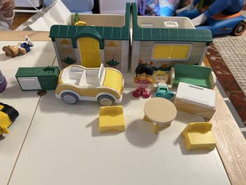 Toy dollhouse acceptable with a car, 2 figures, and furnishings including a array and chairs, acceptable up successful a play area