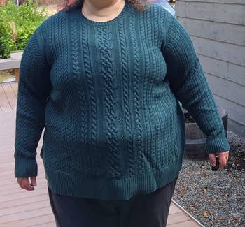 plus size reviewer in green cable knit sweater