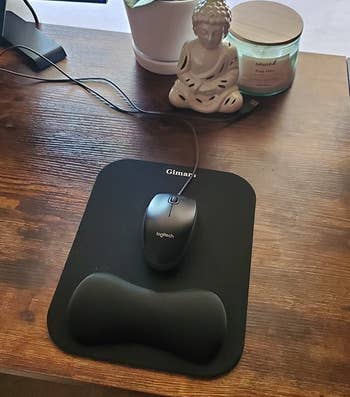reviewer photo of black mouse pad with wrist support on wood desk