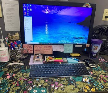 Desk with computer on a black desk mat with a multicolor floral print 