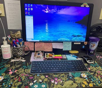 Desk with computer on a black desk mat with a multicolor floral print 