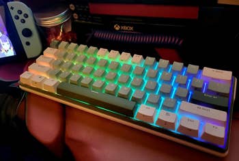 Compact RGB mechanical keyboard next to a game console controller on a desk setup