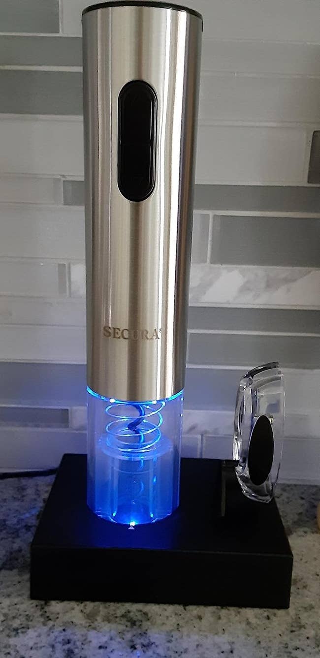 A reviewer's electric bottle opener with blue lights