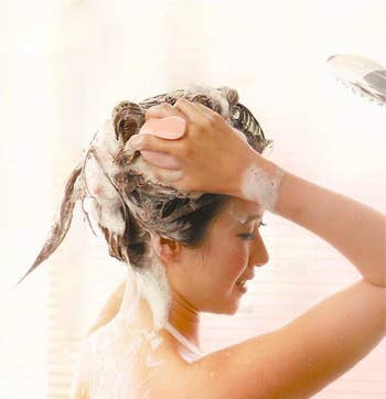 model using the pink scalp massager to shampoo their hair