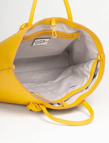 the tote open to show light lining, pockets, and clip closure