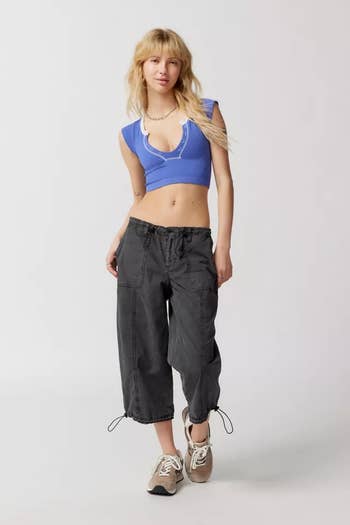 Model in a blue crop top and black cargo pants