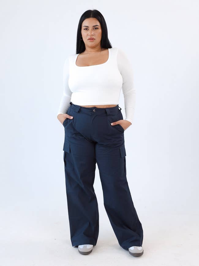 model in white top and navy cargo pants stands with hands in pockets